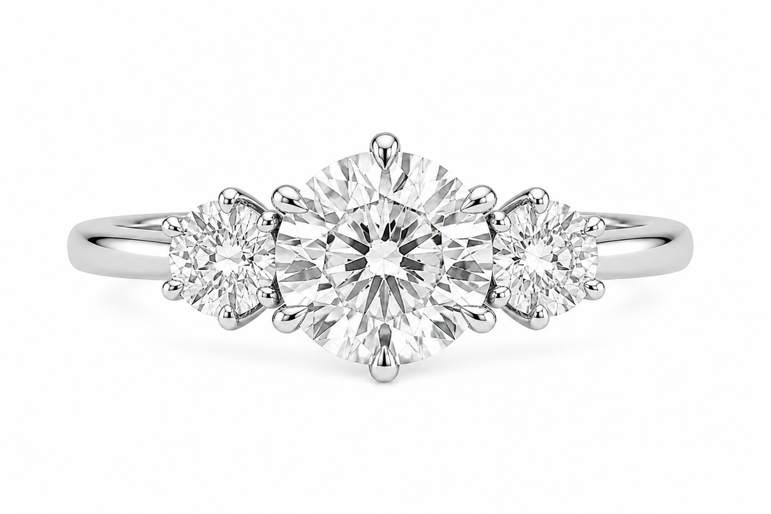 Adelaide three-stone engagement ring with a round center diamond, round side stones, and six claw prongs on a 14K white gold band.