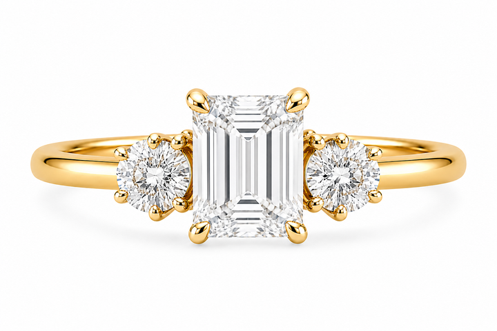 Adelaide 14K yellow gold engagement ring with emerald cut center and round side diamonds.