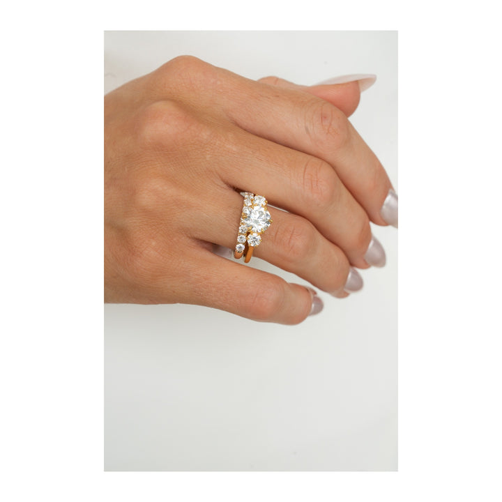 Adelaide three-stone engagement ring with round diamonds and a matching band in 14K yellow gold on a hand.