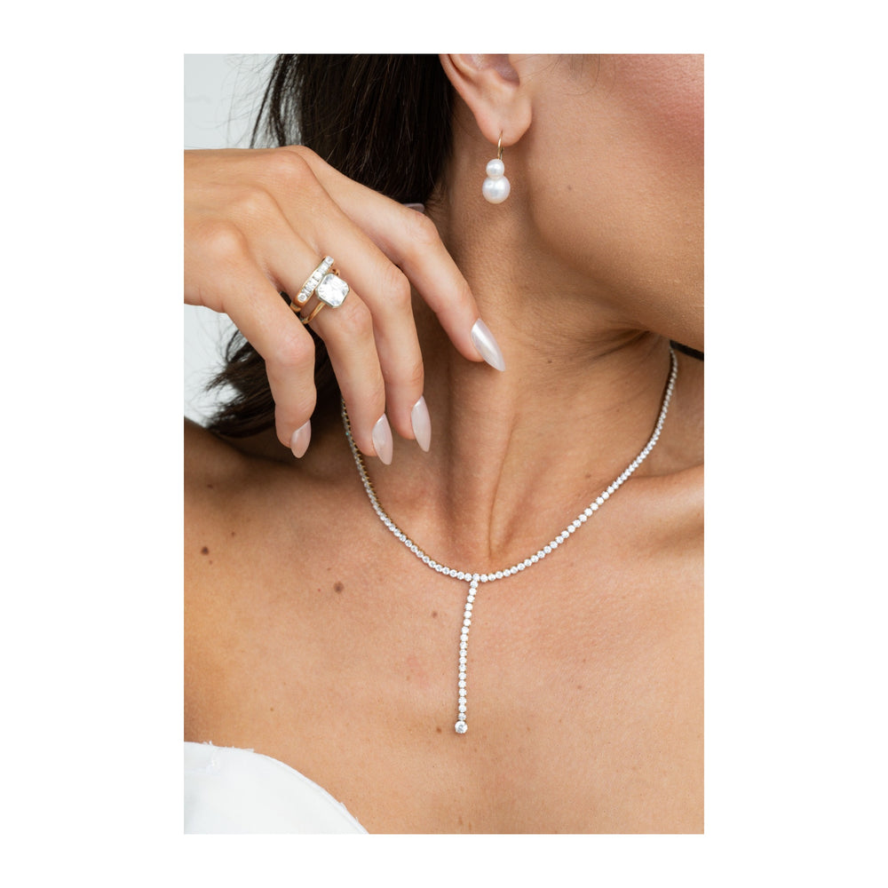 Celeste two-tone 14K yellow and white gold engagement ring with a 2 CT diamond, worn with a diamond necklace and pearl earrings.