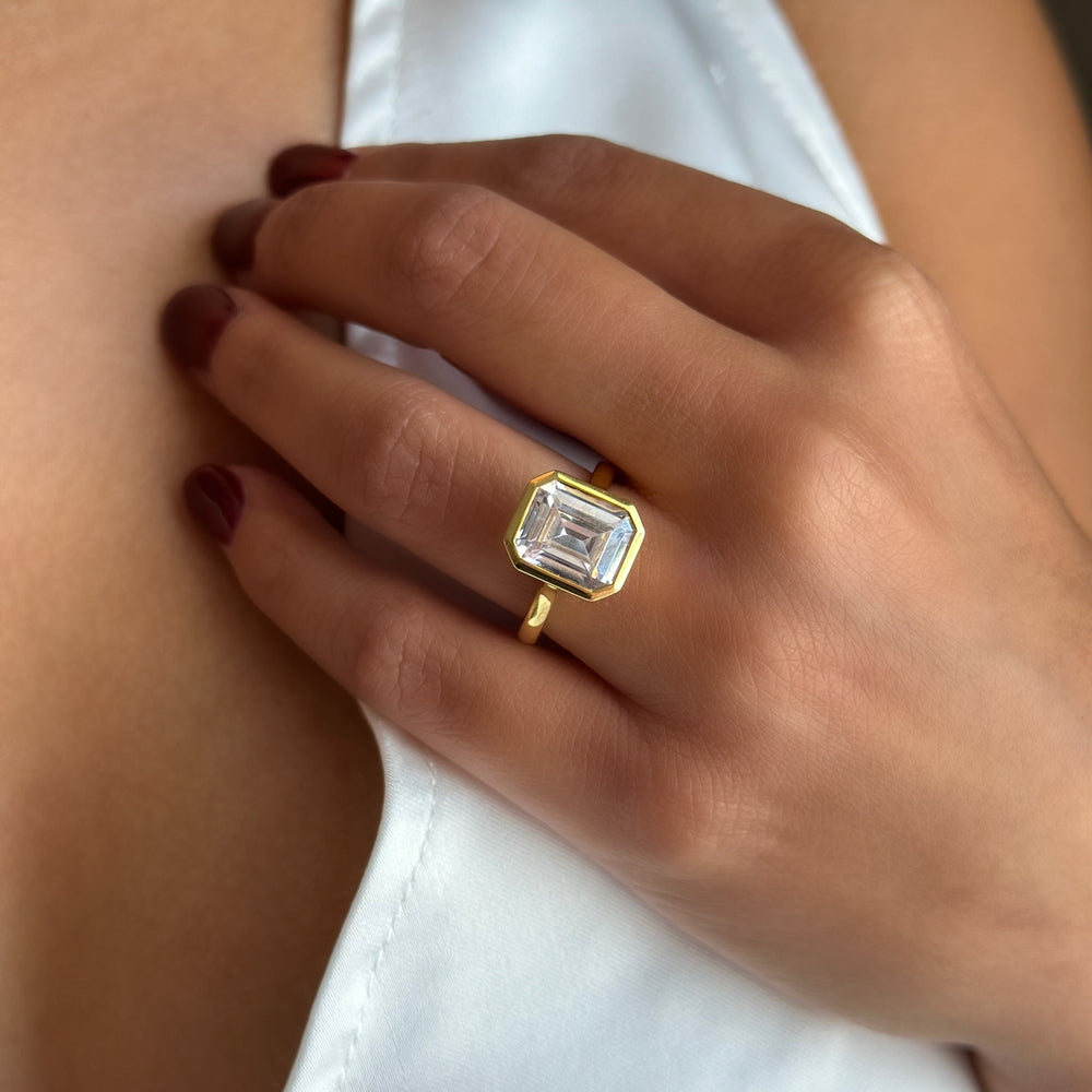 Celine 14K yellow gold engagement ring with a 2 CT emerald-cut diamond in a bezel setting.