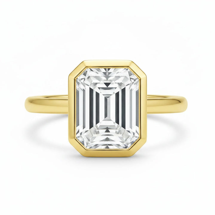Celine Signature Engagement ring with an emerald-cut diamond in a 14K yellow gold bezel setting.