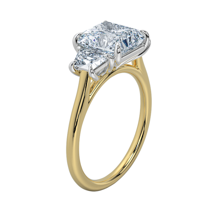 Charlotte engagement ring with an emerald cut center stone and trapezoid side stones on a yellow gold band.