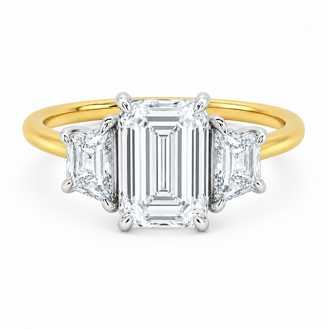 Charlotte three-stone engagement ring with emerald center, trapezoid side diamonds, and a 14K yellow and white gold setting.