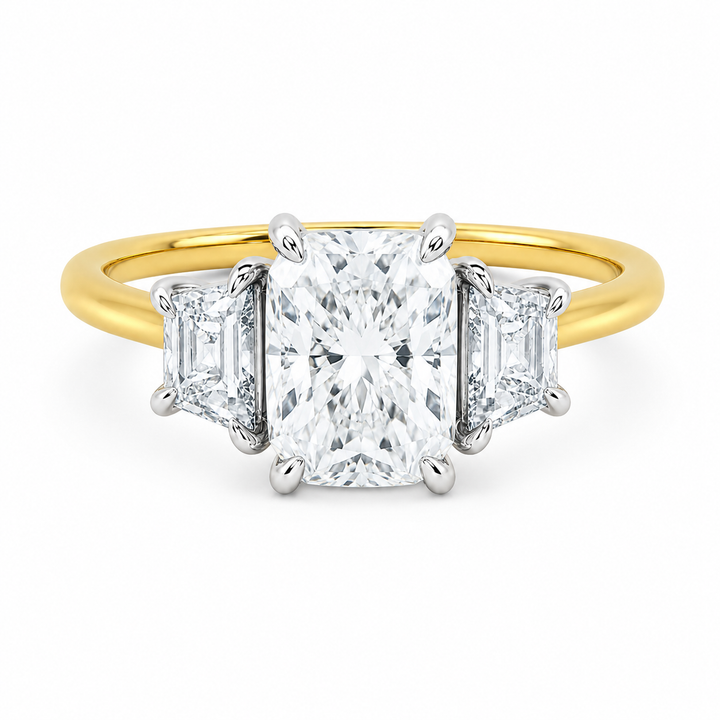 Charlotte three-stone engagement ring with a radiant center diamond, trapezoid side stones, and a two-tone yellow and white gold setting.