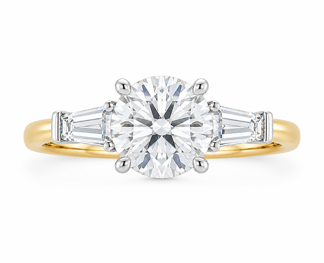 Colette three-stone engagement ring with a round center diamond, tapered baguette side stones, and a two-tone 14K yellow and white gold band.
