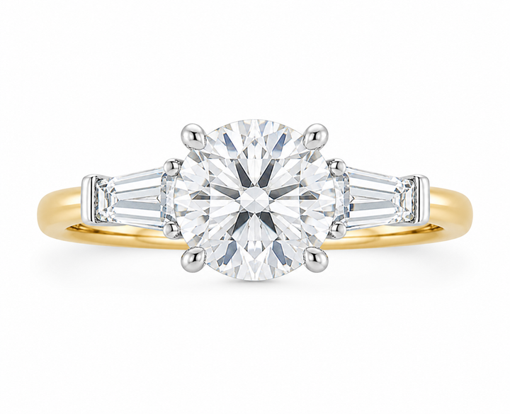 Colette three-stone engagement ring with a round center diamond, tapered baguette side stones, and a two-tone 14K yellow and white gold band.