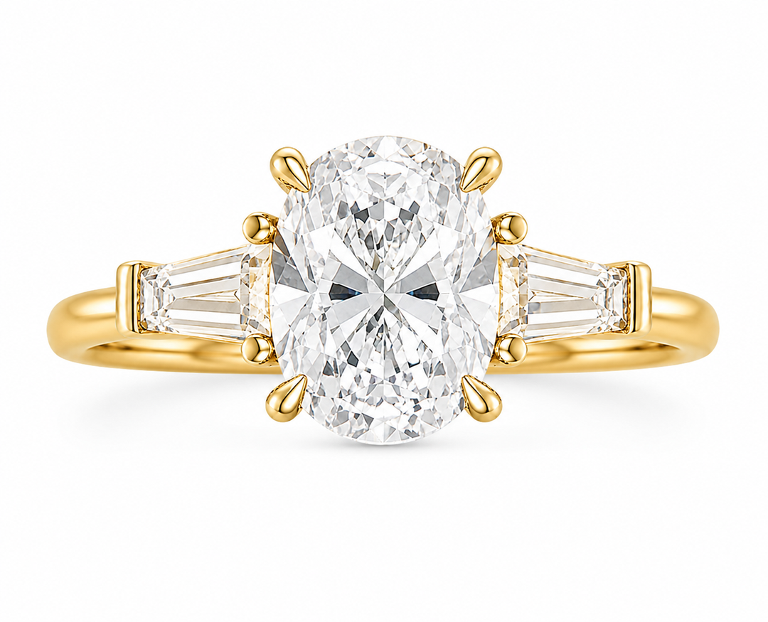 Colette Signature Engagement Style: 14K yellow gold ring with an oval center diamond and tapered baguette side stones.