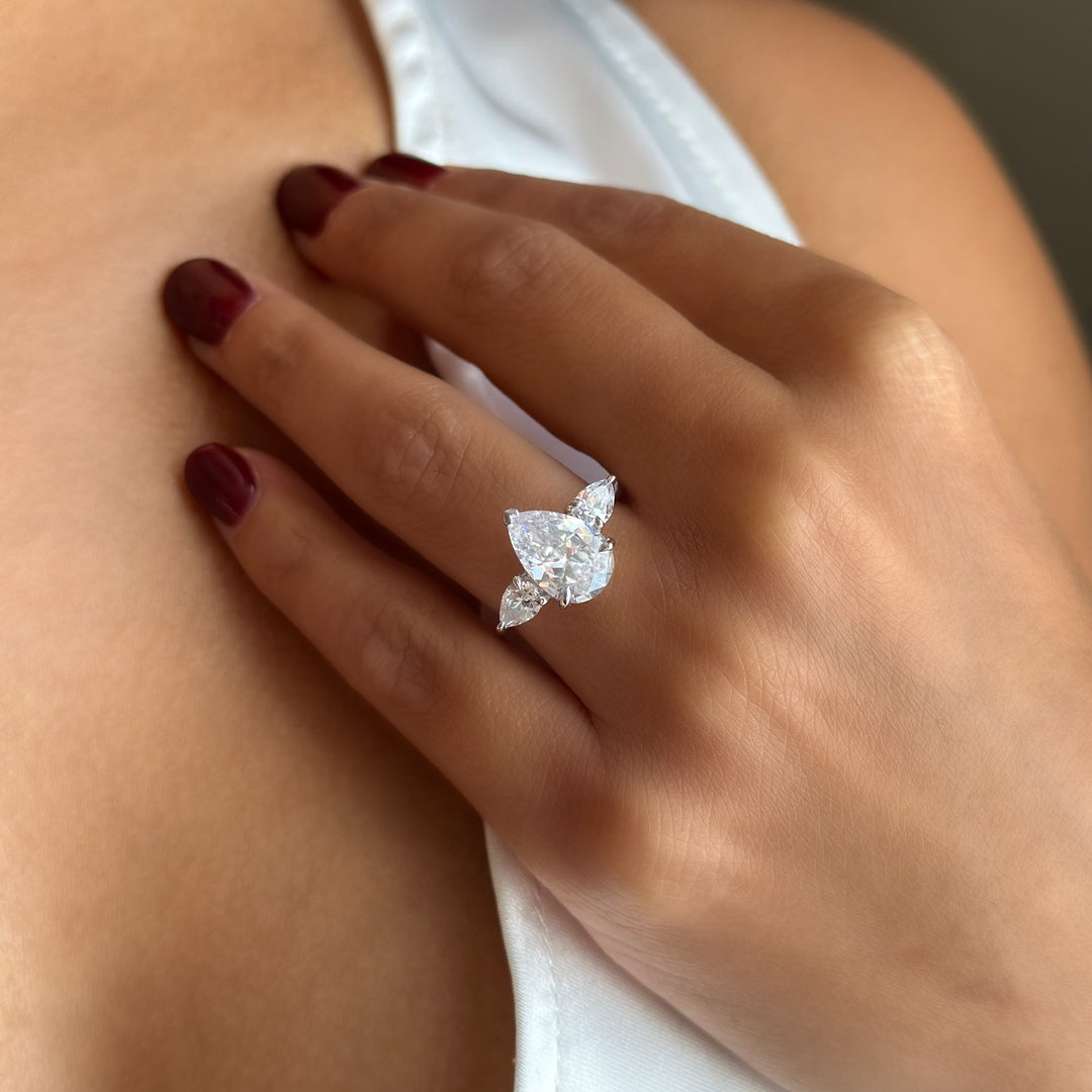 14K white gold Ivy Signature engagement ring with a large pear center diamond and two pear side stones on a woman&