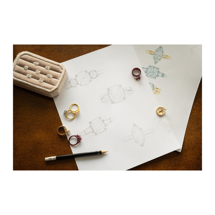 Engagement ring designs, sketches, and finished rings with various diamond shapes on a brown surface.