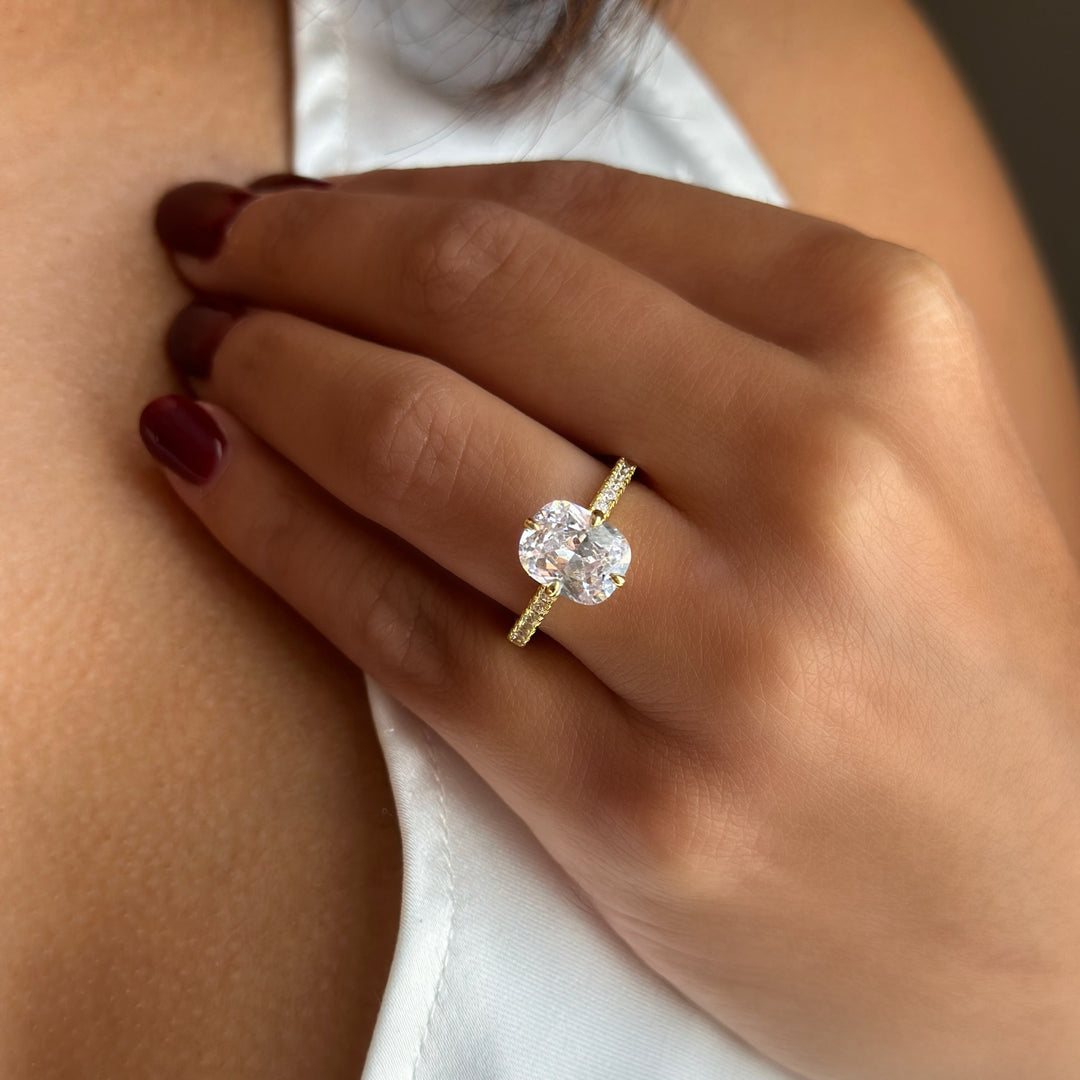 Izzy cushion solitaire engagement ring with a hidden halo, compass setting, and pave band in yellow gold.