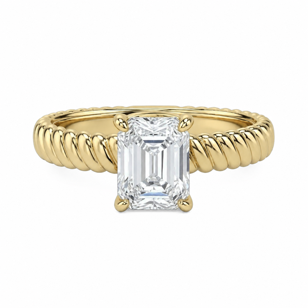 Jenn Signature engagement ring with a solitaire emerald cut diamond and 14K yellow gold rope band.